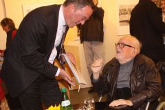 Mainzer Oberbürgermeister Michael Ebling lässt sich Barbara Petermanns Buch „Am Anfang war das Holz“ von dem Künstler Reinhold Petermann signieren.